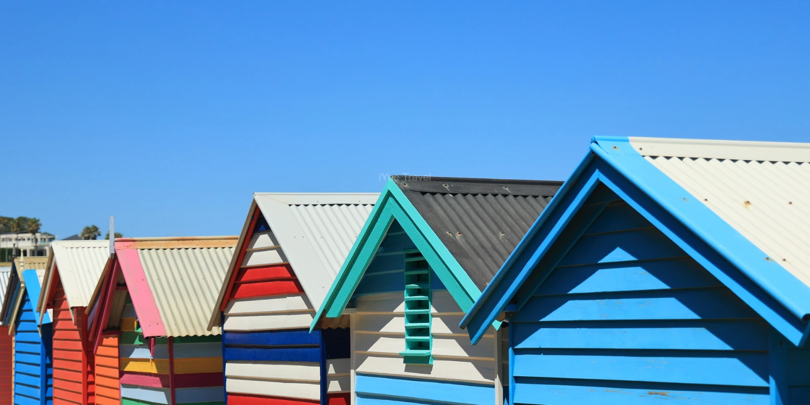 Colourful wooden bathing boxes along Dendy Street Beach, with Port Phillip Bay in the background